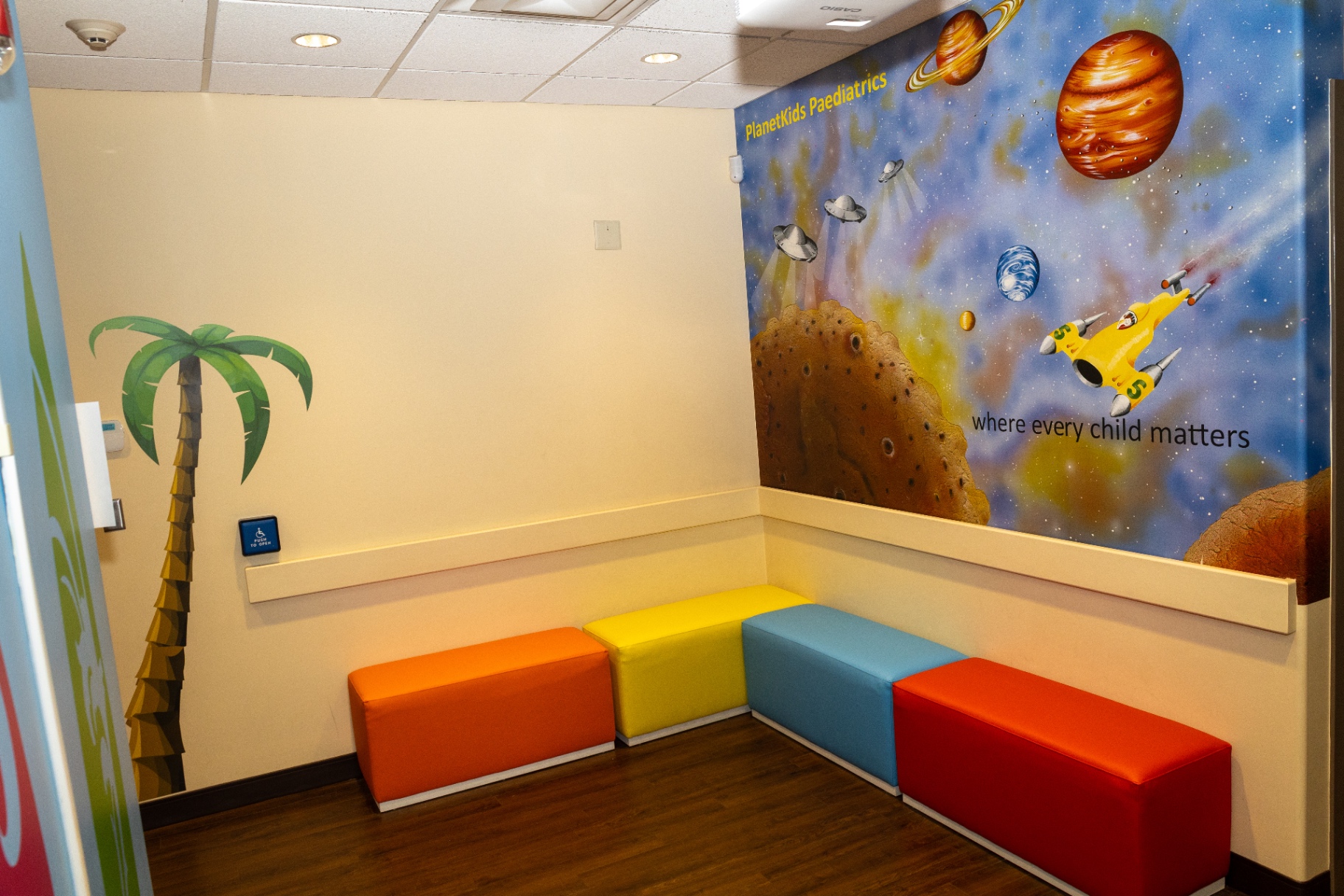 Waiting area with a painted space mural, planets and rocket beside colourful benches