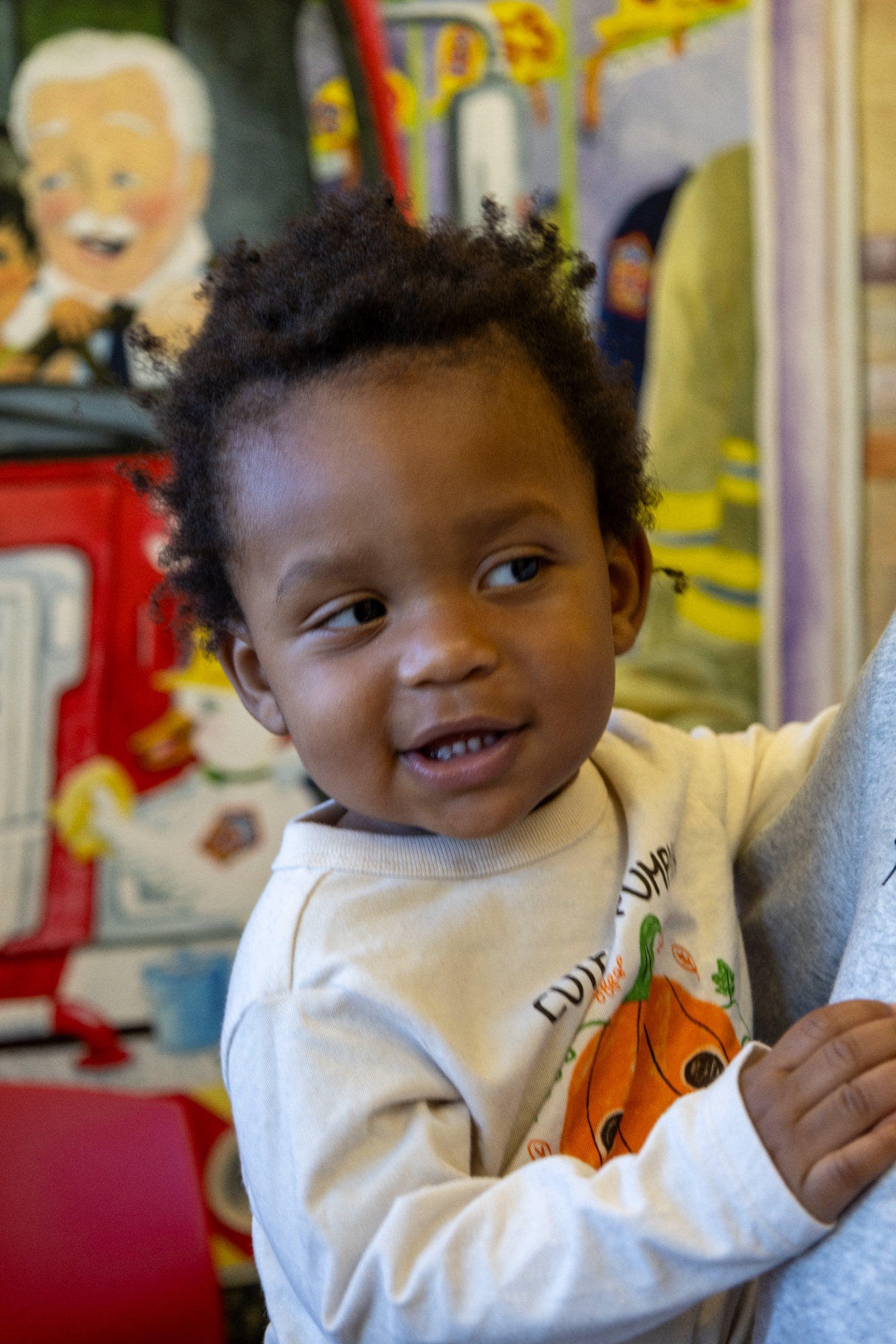 Smiling toddler in front of a fire truck mural in an examination room